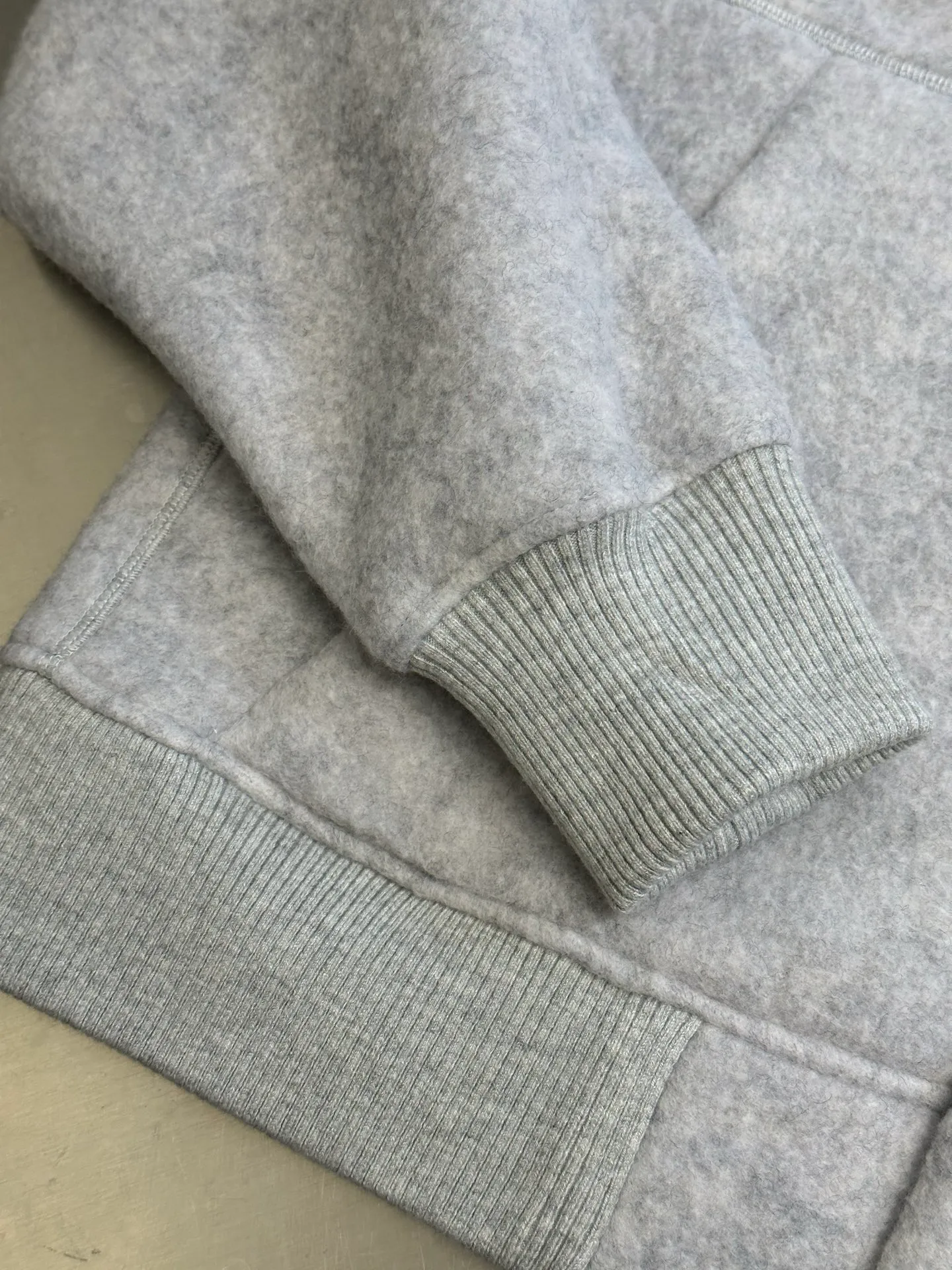 P770 Canada Goose Fleece Badge Button Jacket The main fabric of this jacket is light gray wool blend fabric to improve the fabric's wear resistance, wrinkle resistance and warmth. Wool provides good warmth and a natural feel, while blended fibers enhance the fabric's practicality and durability.  The cutting process needs to ensure that the texture and color of the fabric are evenly distributed, especially with this light gray tone, to avoid chromatic aberrations. The stretchability of wool-blend fabrics needs to be taken into consideration when cutting pieces to ensure dimensional stability of the finished garment.  Use a sewing needle and thread suitable for wool-blend fabrics to avoid damage to the fabric during sewing. The sewing stitches are even and firm to prevent thread stripping.  The temperature needs to be controlled during ironing to avoid high temperature damage to the fabric while keeping the fabric smooth and crisp. The front and back body parts, sleeves and other main parts are stitched with flat seams to ensure a smooth silhouette. Align the fabric texture at the splices to keep the look neat.  The white circular armband on the left arm is an important part of the brand identity and is finely sewn to ensure it is strong and flat.  size：s m l xl